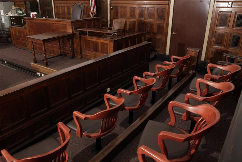 Color photo of a jury box in a courtroom with the judge's bench in the background