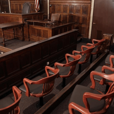 Color photo of a jury box in a courtroom with the judge's bench in the background