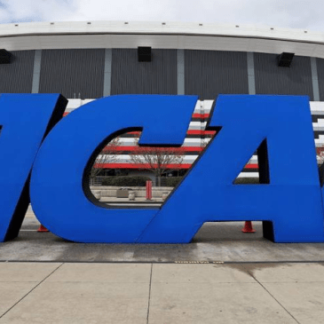 Photo in front of a stadium of a large sculpture of the NCAA logo, consisting of "NCAA" in all capital letters and in blue