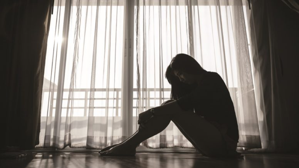 black and white photo of woman sitting on ground hugging knees to chest